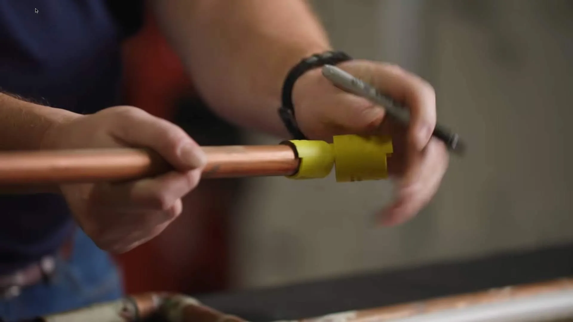 Plumber measuring and marking a copper pipe before cutting it to fit