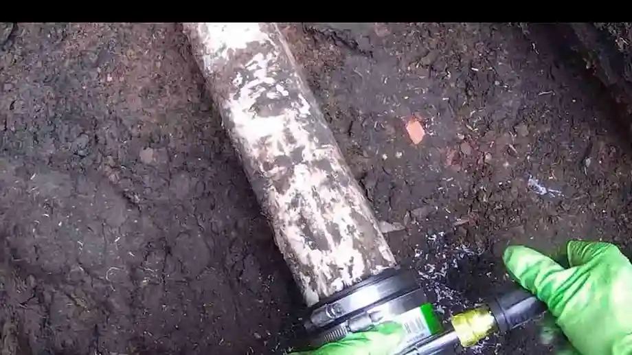 Gloved hands tightening a coupling on a new outdoor cleanout