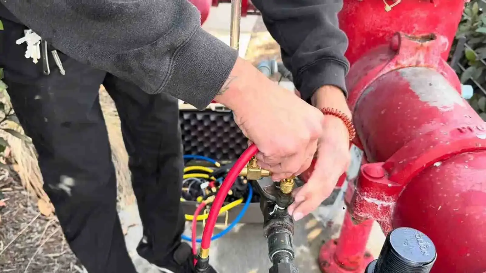 Hands connecting a test hose to a backflow preventer
