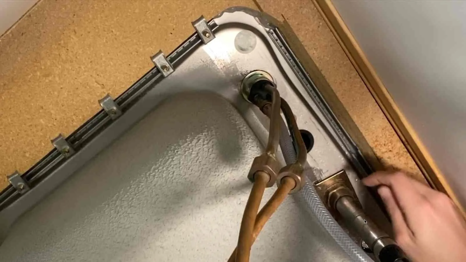 Old faucet being removed under a kitchen sink (before)