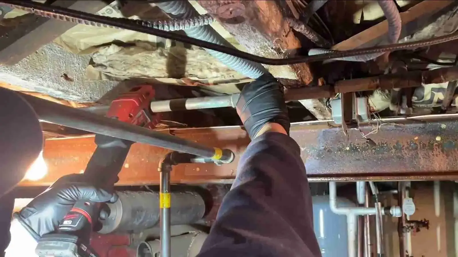 Pipe cutter on a burst pipe under flooded basement joists