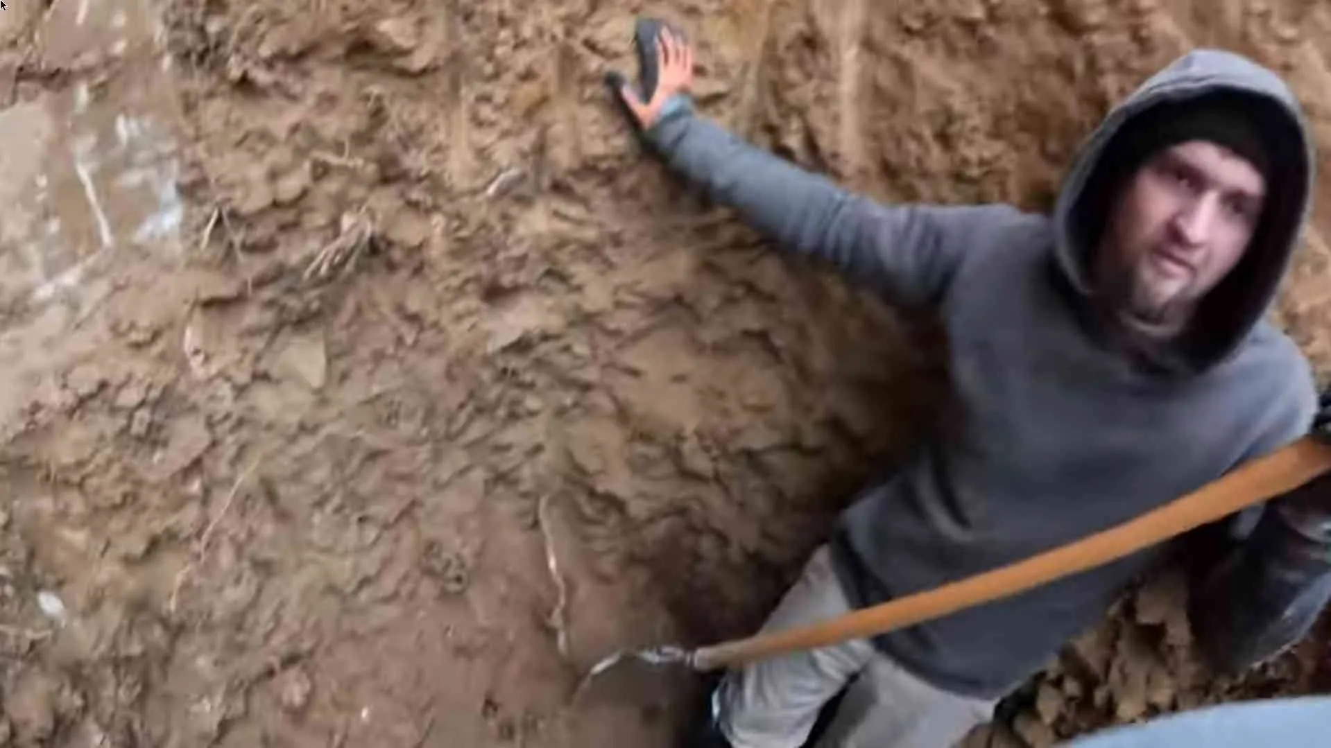 Worker in a deep hand-dug sewer trench