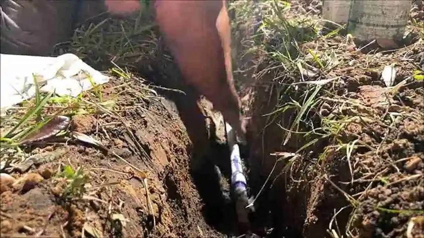 New PVC water main guided into a narrow yard trench