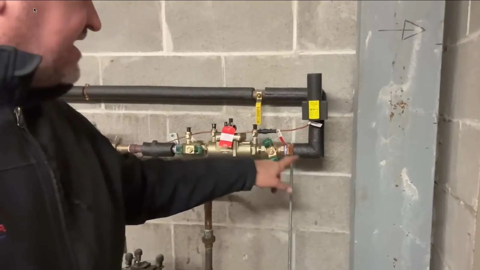 Technician inspecting a backflow preventer in a mechanical room