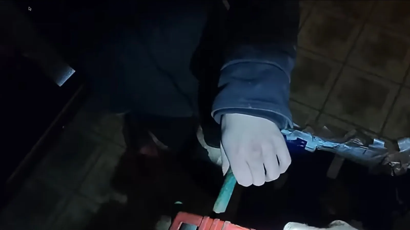 Gloved hands holding a burst pipe section with a press tool