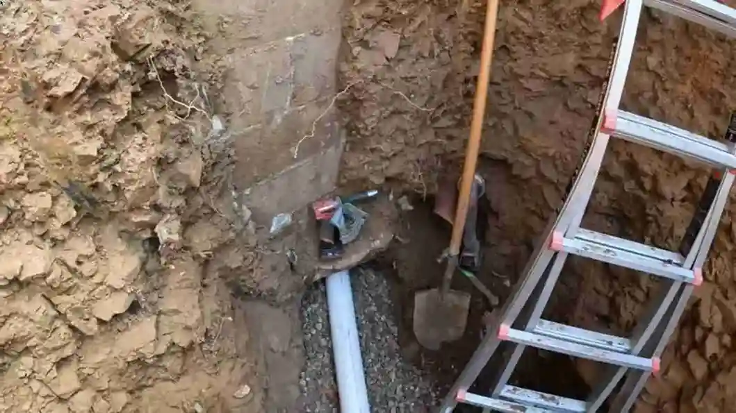 New PVC sewer line on a gravel bed entering a foundation wall