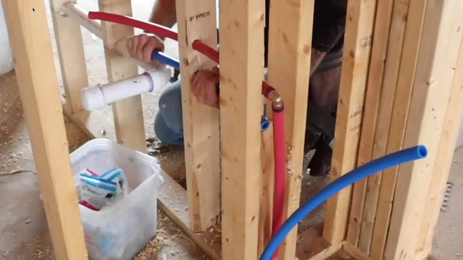 Red and blue PEX water lines connected inside a framed wall