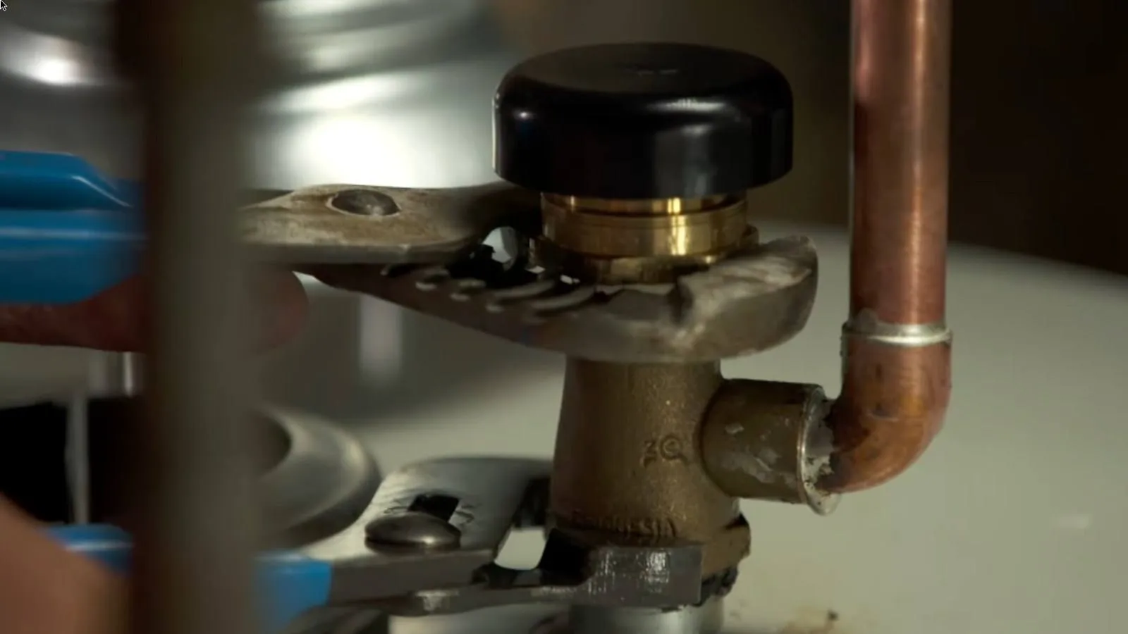 Two wrenches tightening the brass union on a water heater
